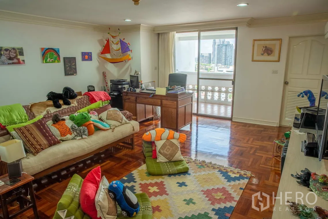 อพาร์ทเมนท์ for rent in Khlong Toei, Bangkok - ห้องครอบครัวหรือห้องเล่นเด็ก มีโต๊ะทำงาน โซฟา และประตูบานเลื่อนออกระเบียง.