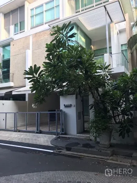 Townhouse for rent or sale in Chatuchak, Bangkok - Modern multi-storey townhouse facade with gated carport and mature tree in Chatuchak.