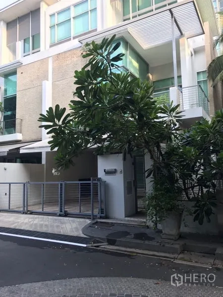 Townhouse for rent or sale in Chatuchak, Bangkok - Modern multi-storey townhouse facade with gated carport and mature tree in Chatuchak.