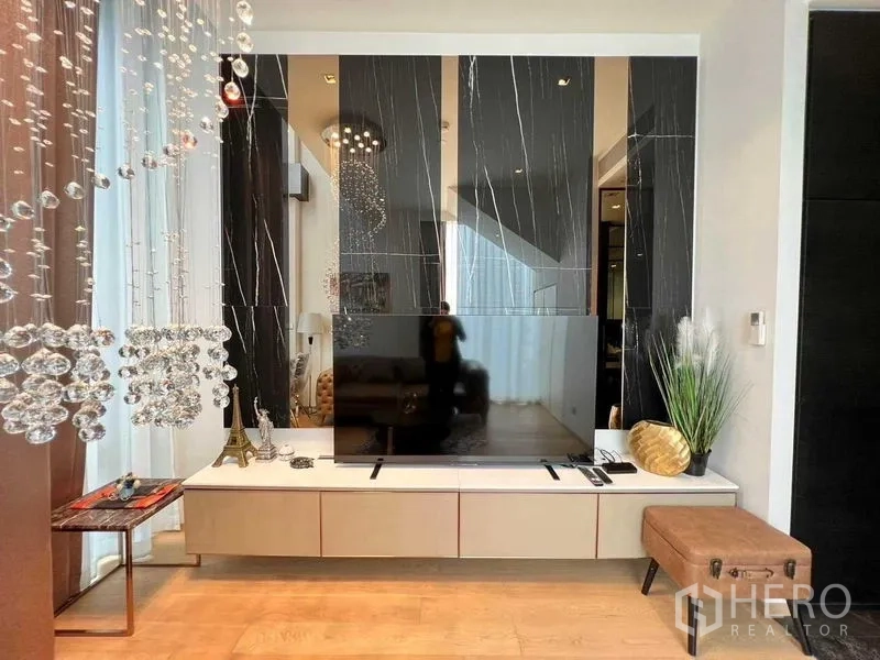Condominium for rent - Close-up of TV console with black marble wall and hanging crystal accents.