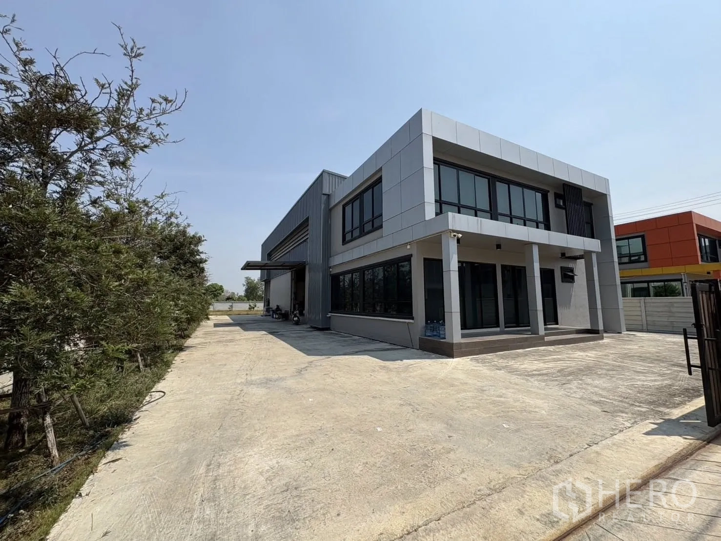 โรงงาน for rent or sale in Bang Len, Nakhon Pathom - มุมมองเฉียงของโรงงานร่วมสมัย กระจกบานใหญ่ และลานหน้ากว้างปูคอนกรีต
