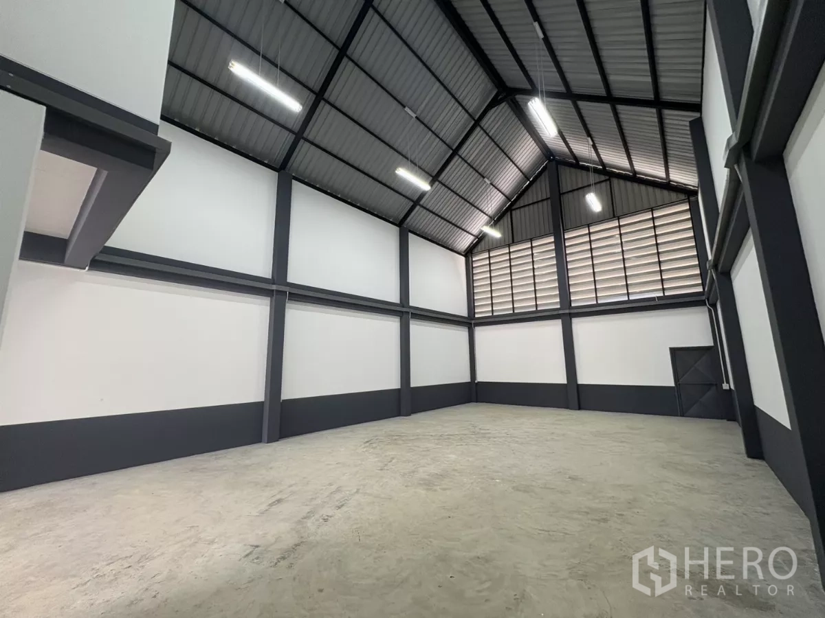 Factory for rent or sale in Bang Bua Thong, Nonthaburi - Large storage area with louvered vent wall and side exit door.