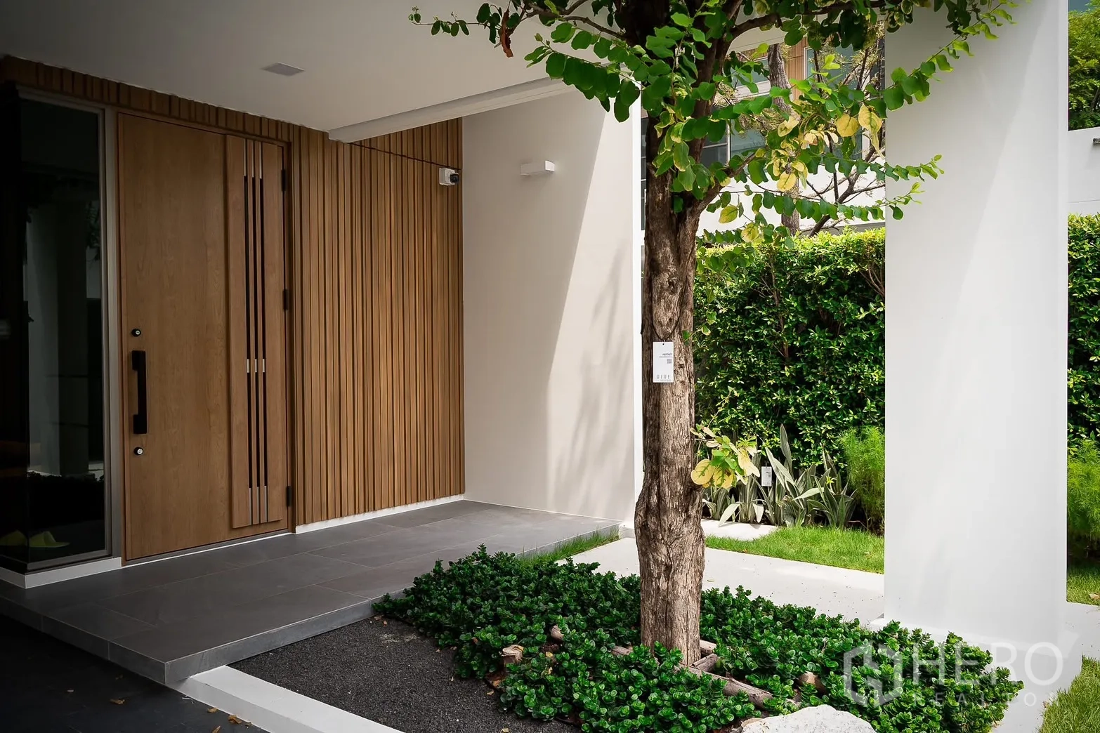 บ้าน ให้เช่าในSaphan Sung, Bangkok - ทางเข้าบ้านร่วมสมัย ประตูไม้และผนังลายซี่ พร้อมสวนต้นไม้เล็ก
