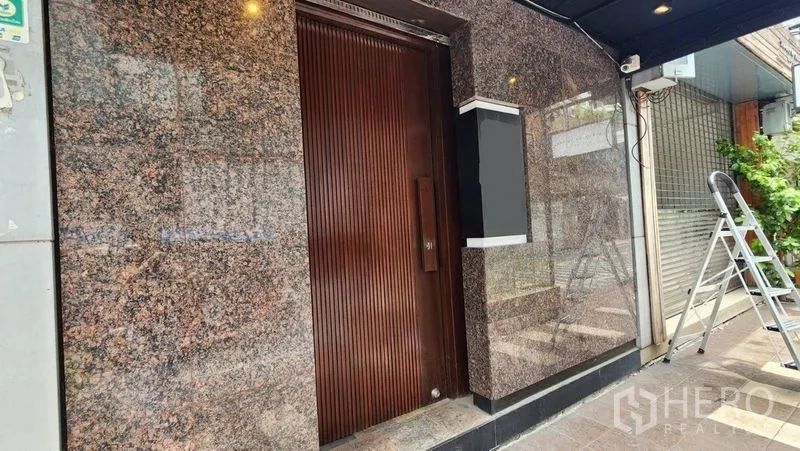 店屋 出租在Khlong Toei, Bangkok - 一层花岗岩外墙主入口，实木门与门牌灯箱。