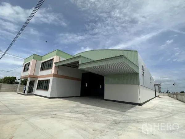 โรงงาน ให้เช่าหรือขายในSai Noi, Nonthaburi - มุมมองภายนอกแสดงหลังคาโถงโหลดสินค้าและลานคอนกรีตกว้างหน้าโกดัง