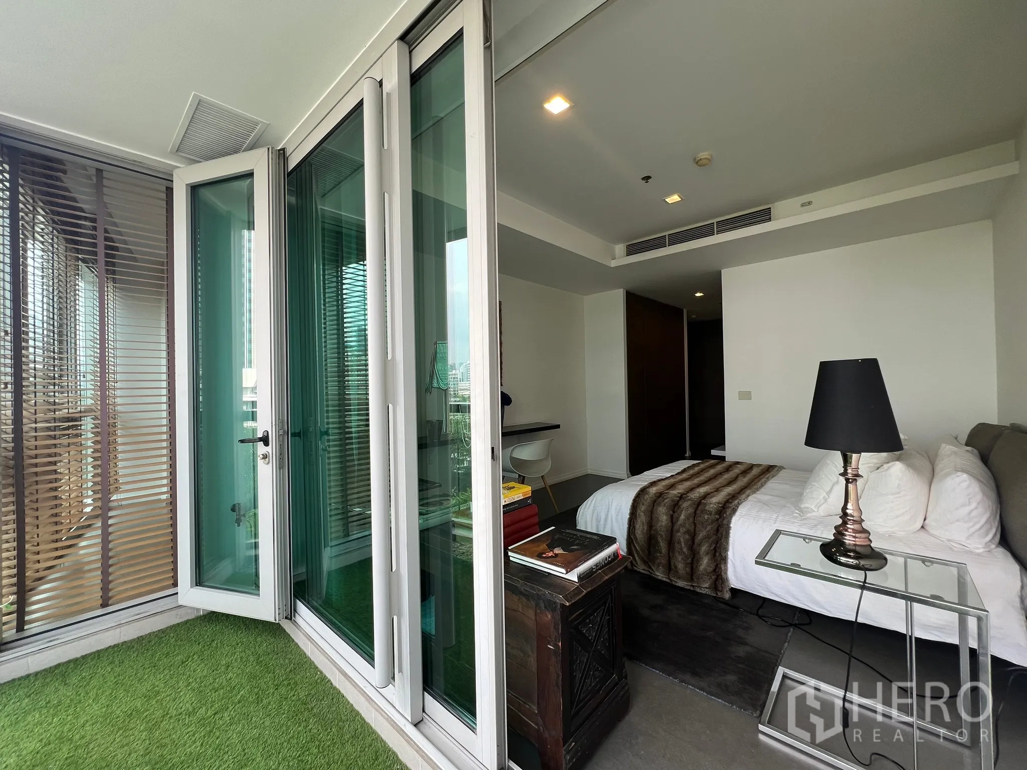 Condominium for sale in Khlong San, Bangkok - Folding glass doors from the balcony into the bedroom with bedside table.