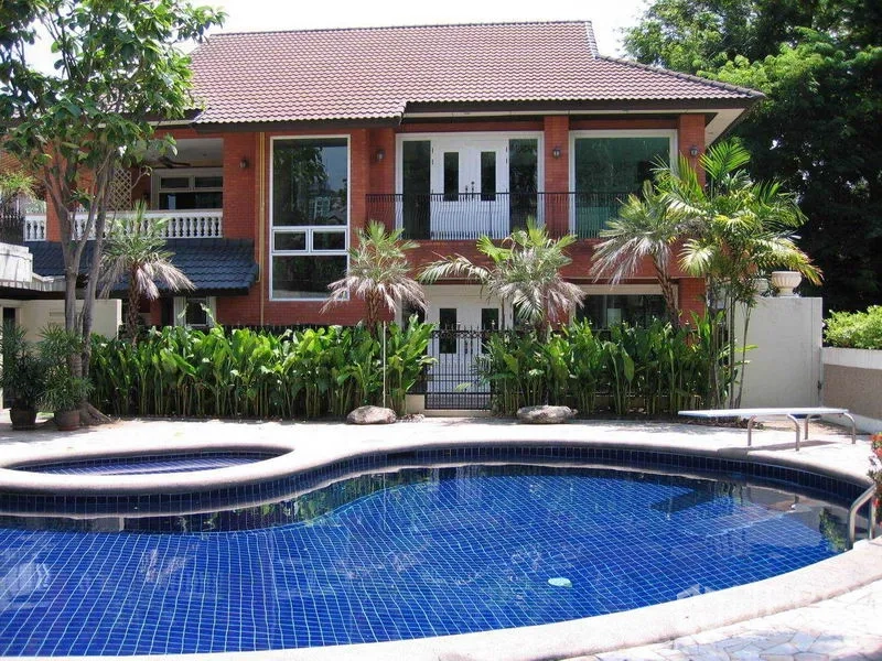 Detached House for rent in Watthana, Bangkok - Two-storey brick detached house with balconies overlooking a freeform blue-tiled private pool and tropical garden.