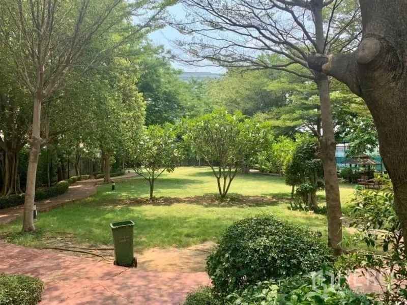 Condominium for rent in Khlong Toei, Bangkok - Shaded landscaped garden with lawn, trees and winding brick pathways.