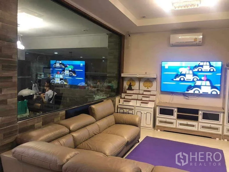 Detached House for rent or sale in Prawet, Bangkok - Living area with large interior window to the kitchen and a wall-mounted TV console.
