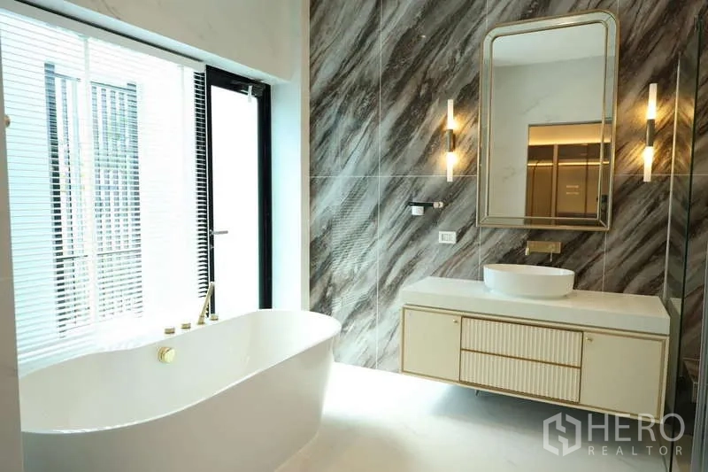Detached House for rent or sale in Saphan Sung, Bangkok - Luxurious bathroom with freestanding bathtub, backlit mirror and marble tiles.