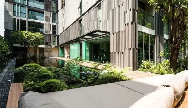 公寓 出租或出售在Watthana, Bangkok - 园林式庭院设有镜面泳池与茂密绿植，旁为玻璃幕墙健身房。
