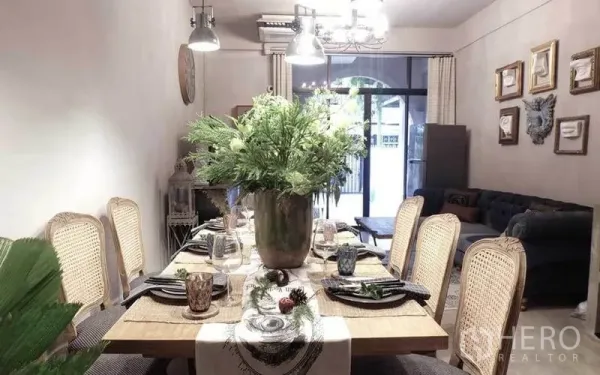 Townhouse for rent in Watthana, Bangkok - Dining room flowing to a living area with sofa and sliding glass doors.