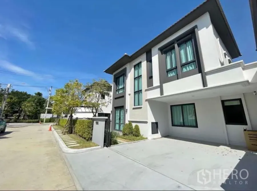 Detached House for rent in Bang Phli, Samut Prakan - Front elevation of the detached home with covered parking and tidy landscaping.