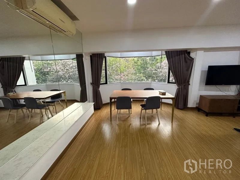 Condominium for rent in Watthana, Bangkok - Dining corner with bay window overlooking greenery and wall mirror.