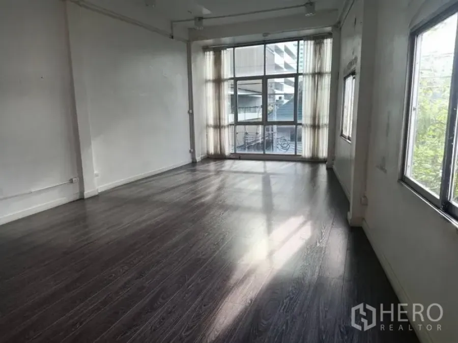 Retail Space for rent in Watthana, Bangkok - Bright empty retail space with dark wood floors and floor-to-ceiling windows.