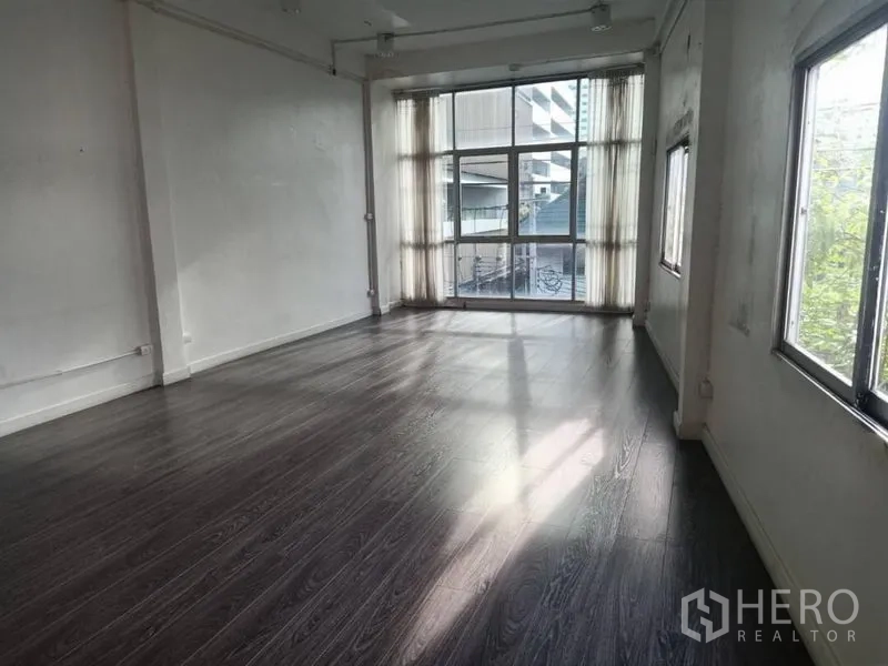 Retail Space for rent in Watthana, Bangkok - Bright empty retail space with dark wood floors and floor-to-ceiling windows.