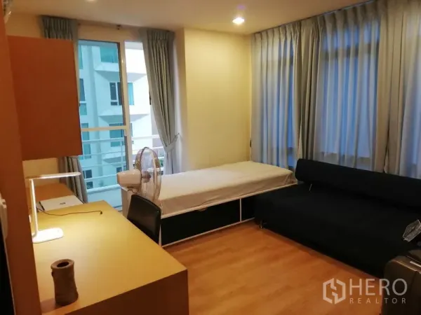公寓 出租在Watthana, Bangkok - 澎蓬地段公寓的次卧，单人床、沙发、书桌与阳台推拉门，采光充足。