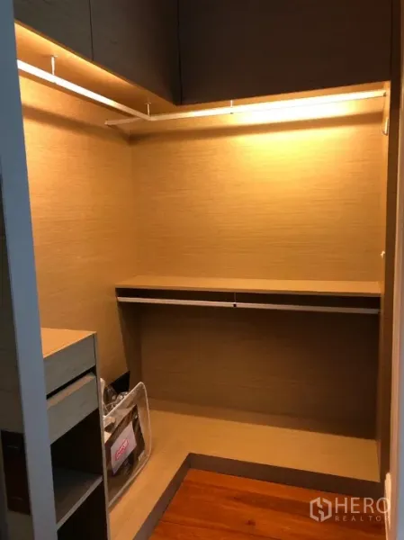 Condominium for rent or sale in Khlong Toei, Bangkok - Built-in walk-in closet with shelves, hanging rails and warm under-cabinet lighting.