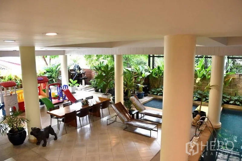 Apartment for rent in Sathon, Bangkok - Covered leisure area with loungers, dining table and children’s play zone beside greenery.