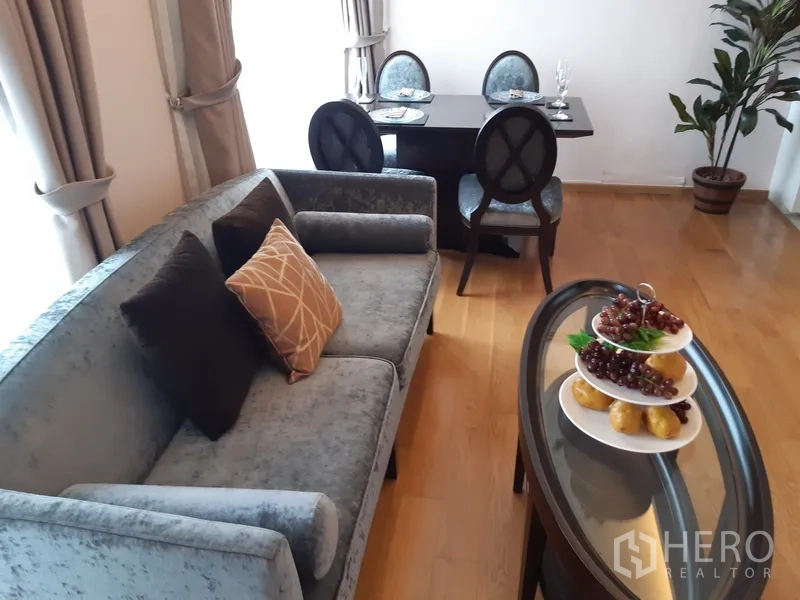 公寓 出租在Watthana, Bangkok - 客厅内设沙发、餐桌与盆栽，木地板温馨明亮。