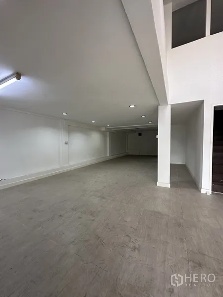 Shophouse for rent in Bang Na, Bangkok - Open-plan ground floor with white walls, recessed lighting, and tiled flooring in a shophouse.