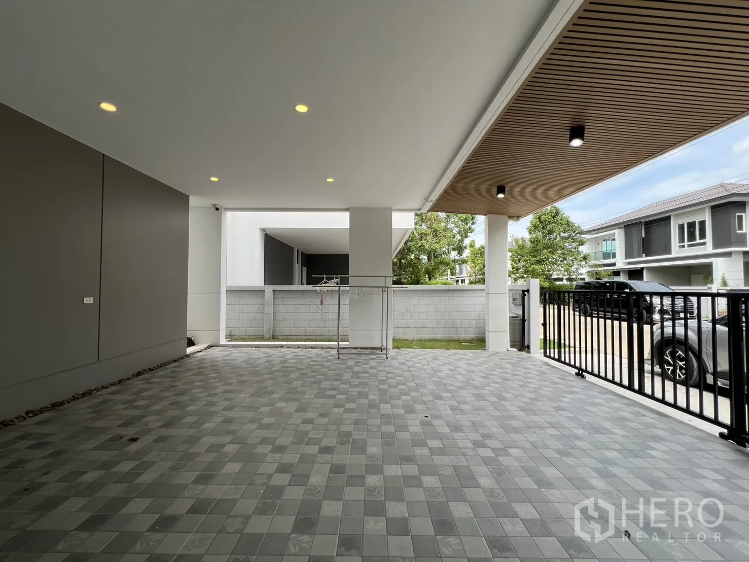 独栋房屋 for rent in Lat Krabang, Bangkok - 宽阔车位朝向后墙，周边可见现代住宅。