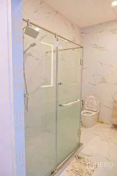 独立式住宅 出售在Lat Phrao, Bangkok - 浅色大理石纹浴室，玻璃淋浴房与坐便器。