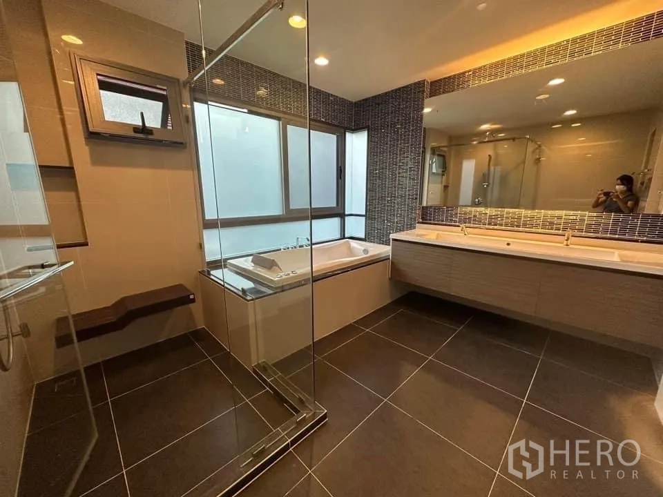 Detached House for rent in Bang Kapi, Bangkok - Master bathroom with bathtub, glass shower and long double vanity beneath mosaic tiles.