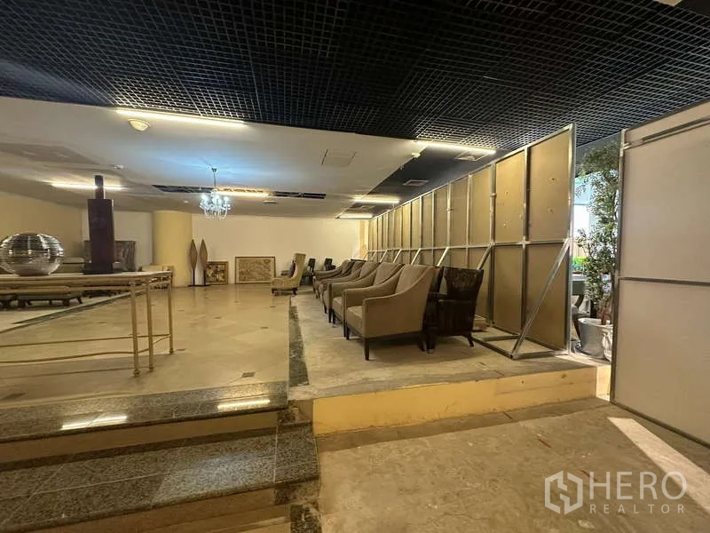 Retail Space for rent - Retail space featuring partition wall, chandelier lighting and seating on a stepped platform.