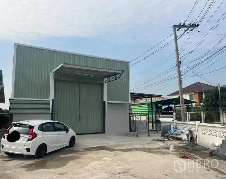 Warehouse for rent in Pak Kret, Nonthaburi - Warehouse exterior with wide sliding door, covered loading canopy, and concrete yard.