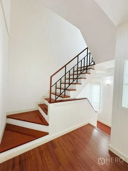 Townhouse for rent in Phra Khanong, Bangkok - Staircase with wooden treads and white walls filled with natural light.