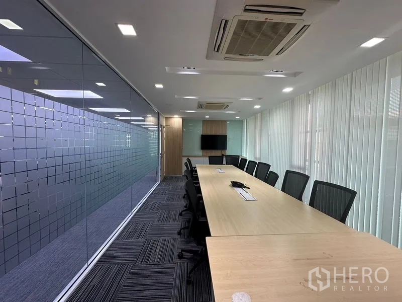 Office Space for rent - Corner private office with desk for two beside tall window and patterned carpet tiles.