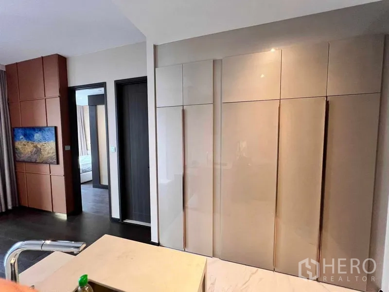 Condominium for rent in Watthana, Bangkok - Living area with built-in wardrobes, wall paneling, and entry to the bedroom.