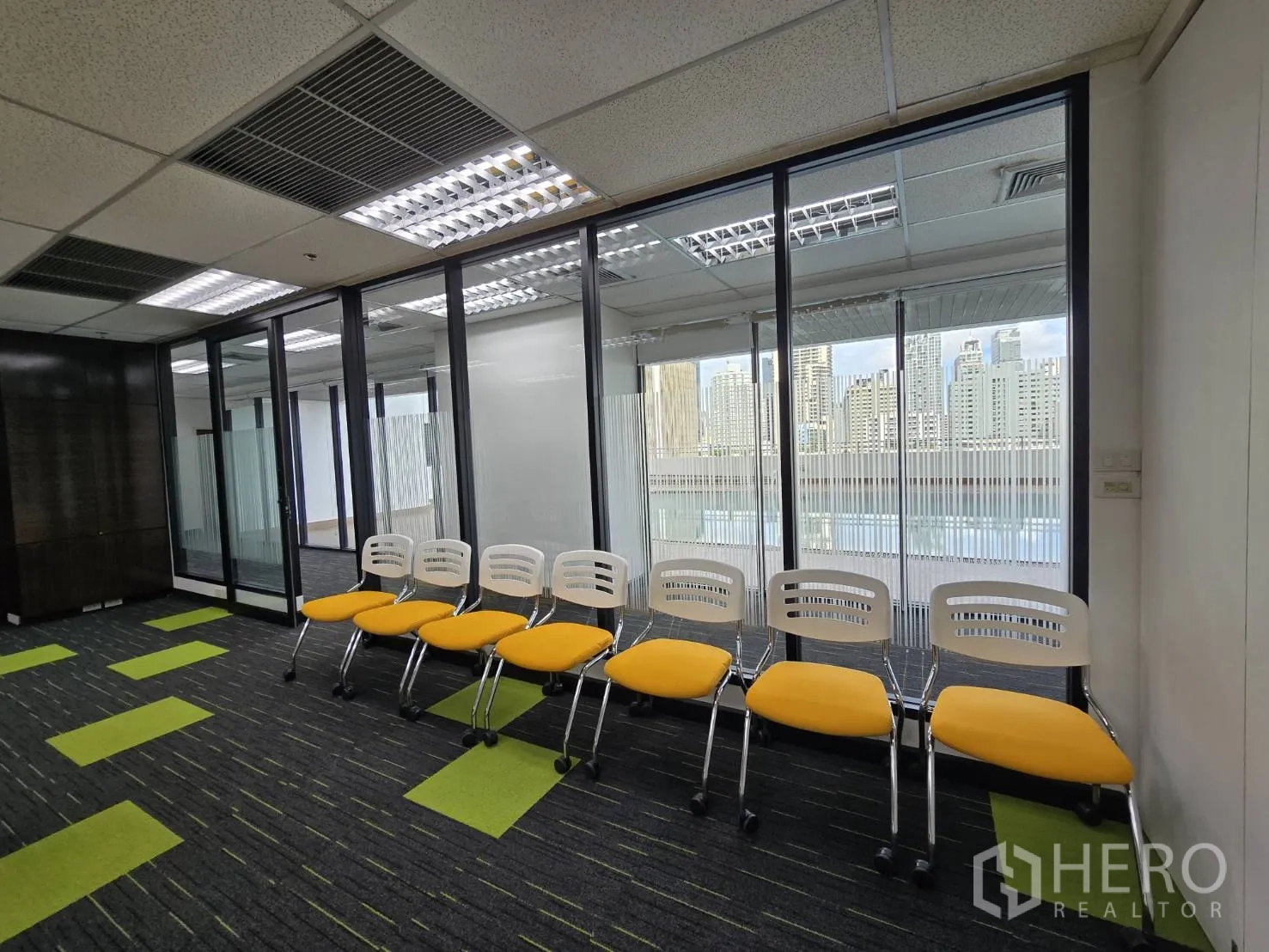 ออฟฟิศ for rent in Watthana, Bangkok - แถวเก้าอี้สีเหลืองติดผนังกระจกพร้อมวิวสกายไลน์.