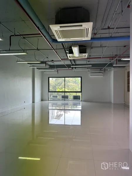 Office Space for rent in Khlong Toei, Bangkok - Open-plan 90 sqm office with glossy tile floors, exposed ceiling ducts, cassette air-con, and a large window with green views.