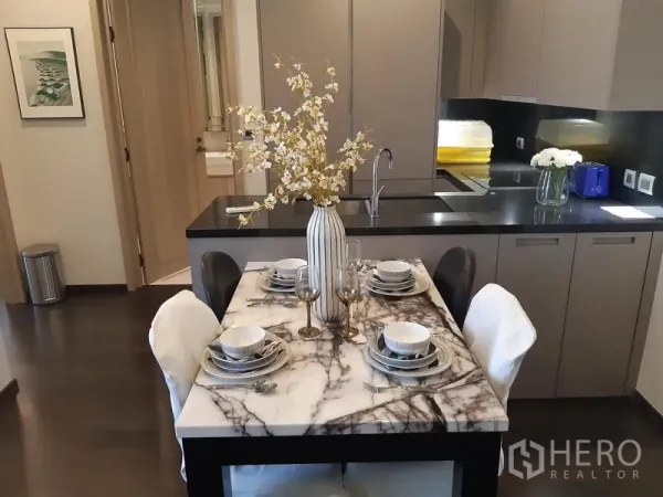 Condominium for rent in Watthana, Bangkok - Marble-top dining table set for four beside a sleek grey kitchen.