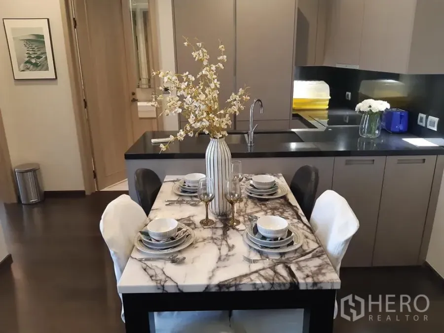 Condominium for rent in Watthana, Bangkok - Marble-top dining table set for four beside a sleek grey kitchen.