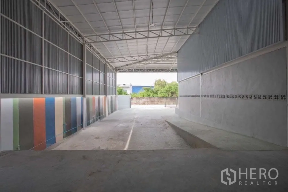 Warehouse for rent in Lat Krabang, Bangkok - Spacious covered loading area with high roof, ramp access and colorful side wall panels.