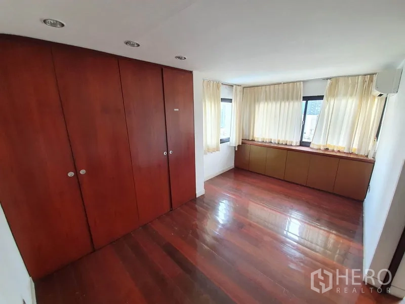 公寓 出售在Watthana, Bangkok - 次卧配木地板、内置衣柜与转角窗。