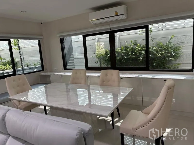 Detached House for sale in Saphan Sung, Bangkok - Dining area with marble table, upholstered chairs and wide windows.