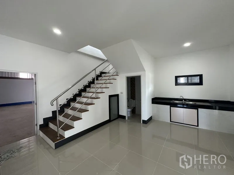 Factory for rent or sale in Sai Noi, Nonthaburi - Ground‑floor office area with tiled floor, pantry counter, staircase and restroom.