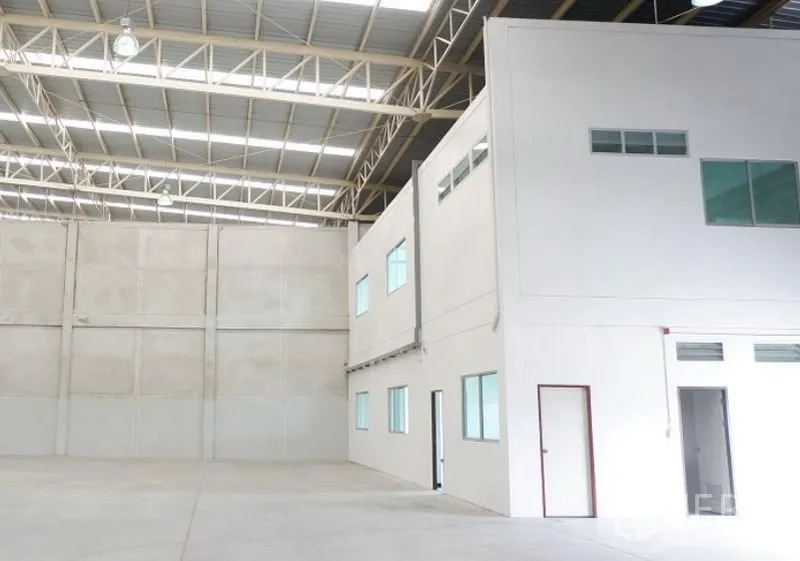 Factory for rent in Pluak Daeng, Rayong - High-ceiling warehouse interior with a two-storey built-in office, steel truss roof and polished concrete floor.