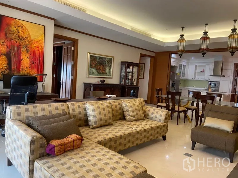 Condominium for rent in Sathon, Bangkok - Lounge view toward dining and kitchen with patterned sofa, glass display cabinet and hanging lantern lights.