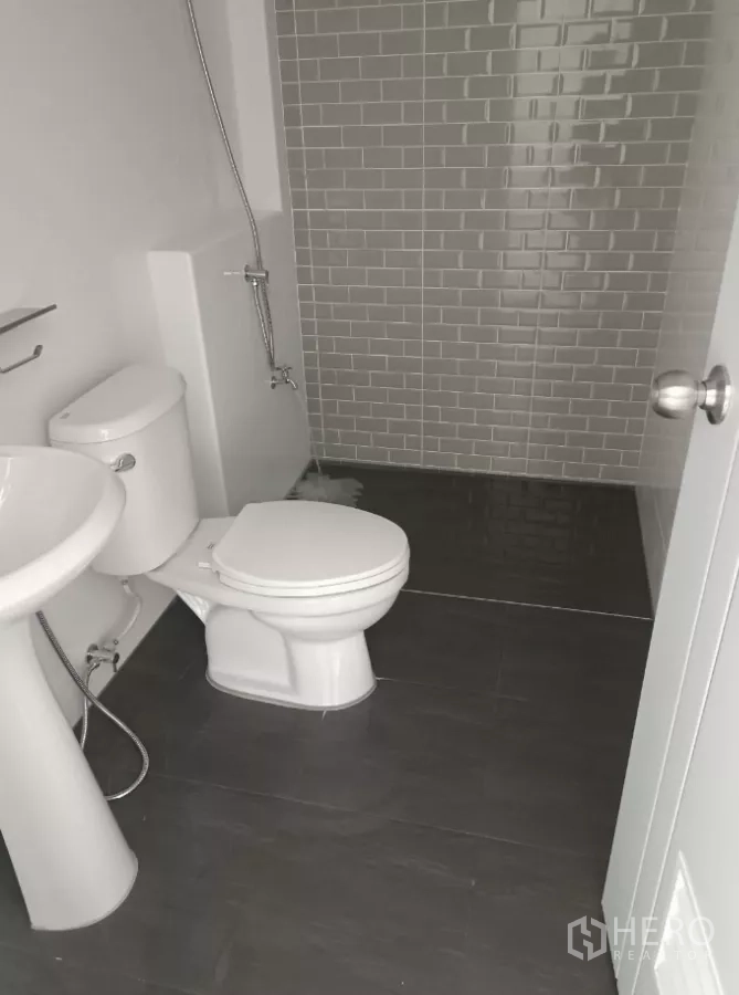 Factory for rent or sale in Bang Yai, Nonthaburi - Clean bathroom with toilet, pedestal sink, and tiled shower corner.