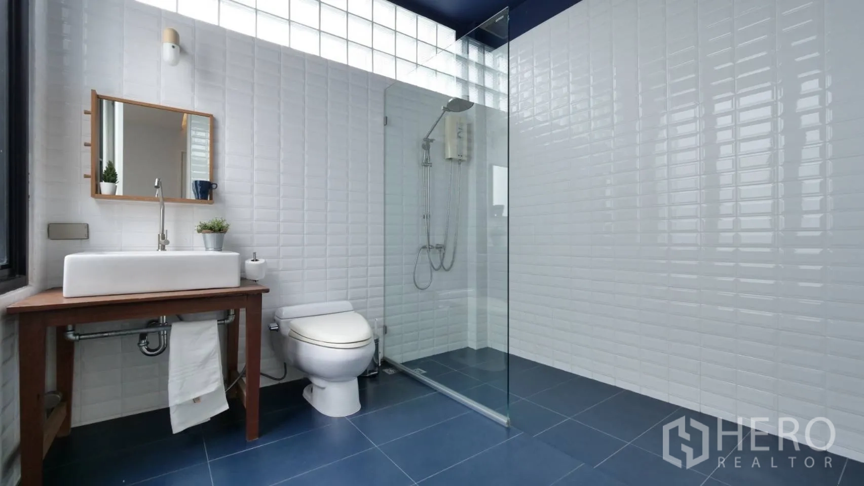 Townhouse for rent in Huai Khwang, Bangkok - Minimalist bathroom with blue floor tiles, walk-in glass shower and wooden vanity.