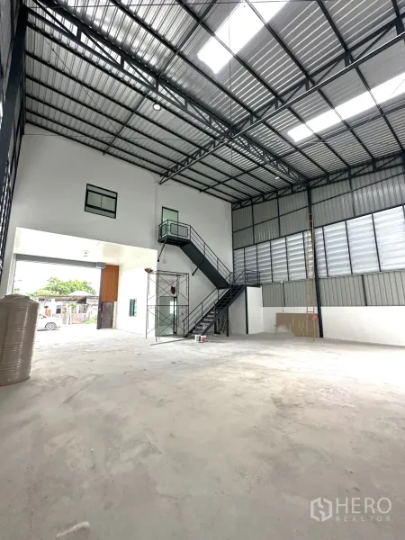 คลังสินค้า ให้เช่าหรือขาย - ภายในโกดังมองไปทางประตูหน้า มีบันไดเหล็กและโครงหลังคาสูง