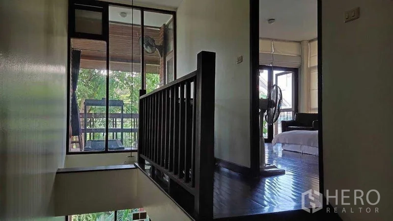 Detached House for sale in Suan Luang, Bangkok - Upstairs landing with black railing and a small balcony facing trees.