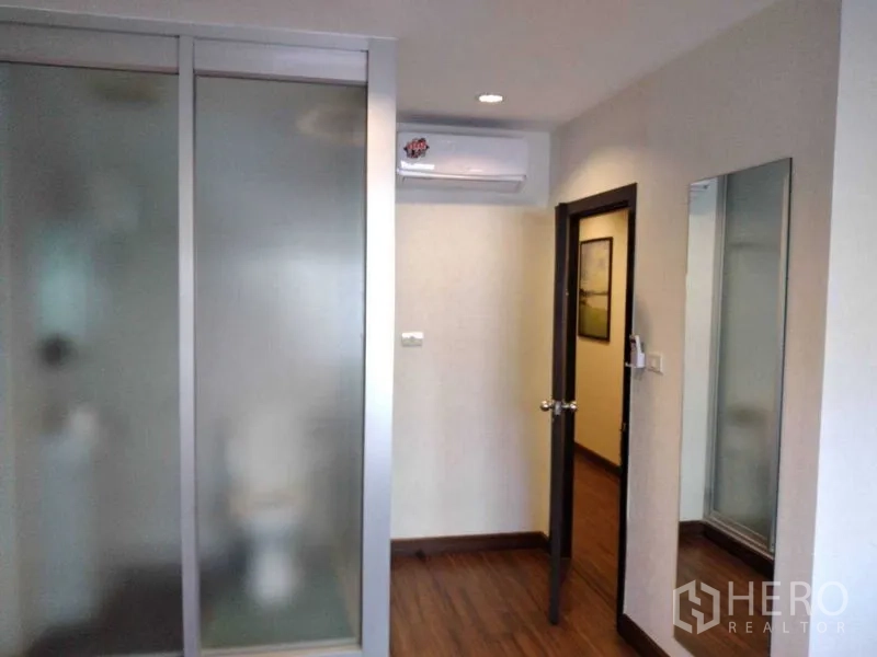 Shophouse for rent in Watthana, Bangkok - Room corner with frosted glass partitions, wall mirror, and air conditioner above the doorway.