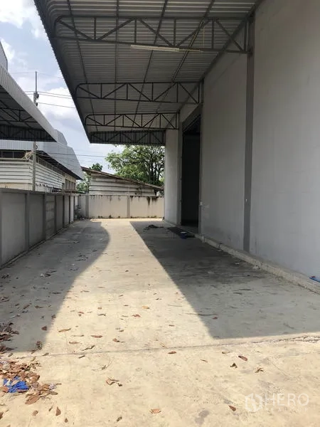 Factory for rent in Lam Luk Ka, Pathum Thani - Opposite covered loading zone with concrete driveway and roof canopy for trucks.