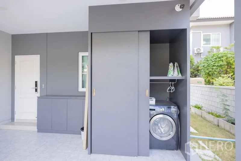 Detached House for rent or sale in Bang Phli, Samut Prakan - Covered laundry and storage zone with sliding cabinet and front-load washer.